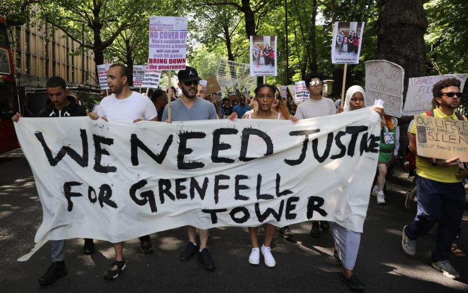 Protesters hold signs calling for justice for the victims of the Grenfell Disaster  - Credit: Dan Kitwood/Getty