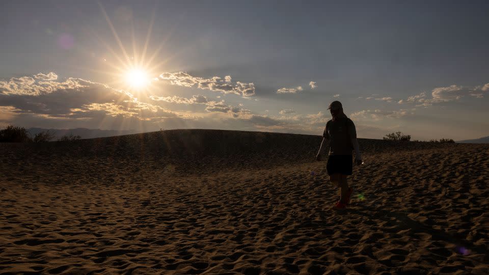 A tourist hikes in the Mesquite Flat Sand Dunes in Death Valley National Park, near Furnace Creek, during a heatwave impacting Southern California on July 7, 2024. - Etienne Laurent/AFP/Getty Images