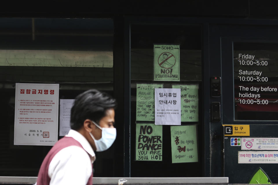 A man waring a face mask passes by notices at the entrance of a temporary closed dance club in Seoul, South Korea, Sunday, May 10, 2020. South Korea on Friday advised nightclubs and similar entertainment venues to close for a month and may delay the reopening of schools after linking more than a dozen new coronavirus infections to clubgoers in the capital. The signs read " Temporary closed," right and "the Seoul city emergency administrative order to prohibit gathering," left. (AP Photo/Ahn Young-joon)