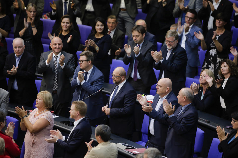 Former European Parliament President and former Social Democratic Party chairman Martin Schulz, center, receives standing ovations from other lawmakers after an intervention during a plenary session of the German parliament Bundestag about the budget 2019, in Berlin, Wednesday, Sept. 12, 2018. (AP Photo/Markus Schreiber)