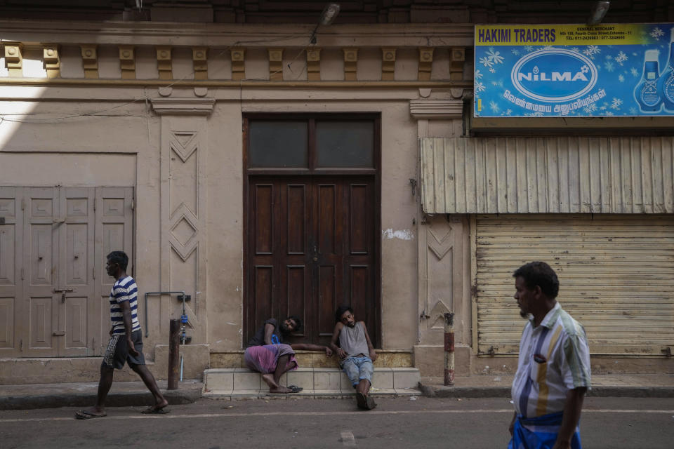 Laborers nap by a closed shop as they wait for work at a wholesale market in Colombo, Sri Lanka, Sunday, June 26, 2022. Sri Lankans have endured months of shortages of food, fuel and other necessities due to the country's dwindling foreign exchange reserves and mounting debt, worsened by the pandemic and other longer term troubles. (AP Photo/Eranga Jayawardena)