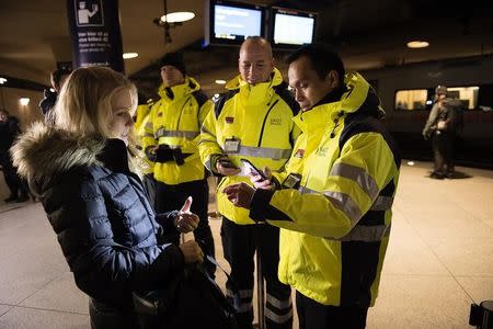 Security staff check a traveller's identification at Kastrups train station outside Copenhagen, Denmark January 4, 2016. REUTERS/Nils Meilvang/Scanpix Denmark