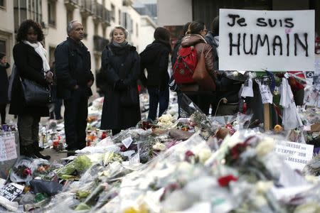 People pay respects to the victims of last week's attacks by Islamic militants in front of the offices of weekly satirical newspaper Charlie Hebdo in Paris January 14, 2015. The pancart reads "I'm human". REUTERS/Gonzalo Fuentes