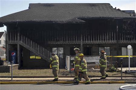 Firefighters walk past the charred remains of the Mariner's Cove Inn in Point Pleasant Beach, New Jersey, March 21, 2014. REUTERS/Charles Mostoller