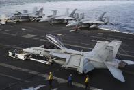 In this Monday, March 20, 2017 photograph, crew reposition an F-18 fighter jet on the USS George H.W. Bush as it travels toward the Strait of Hormuz. The arrival of the nuclear-powered aircraft carrier to the Persian Gulf marks the first such deployment under new U.S. President Donald Trump. (AP Photo/Jon Gambrell)
