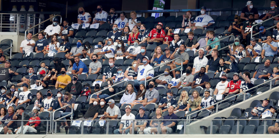 Fans in a section at AT&T Stadium varying between wearing and not wearing masks with very few empty seats between them.