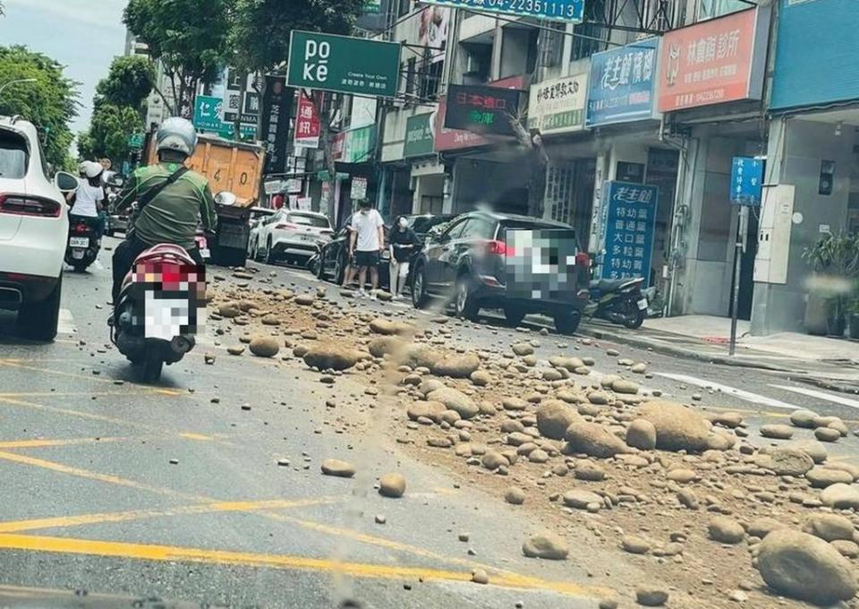 一輛砂石車載著碩大的石頭與黃砂，行經台中市重要交通道路崇德路一段時，砂石車後斗門突然鬆開，大量砂石傾洩於路面。（記者陳金龍翻攝）