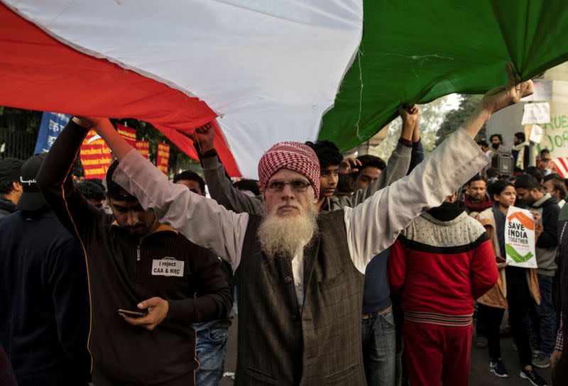 Demonstrators hold the national flag of India as they attend a protest against a new citizenship law, outside the Jamia Millia Islamia university in New Delhi