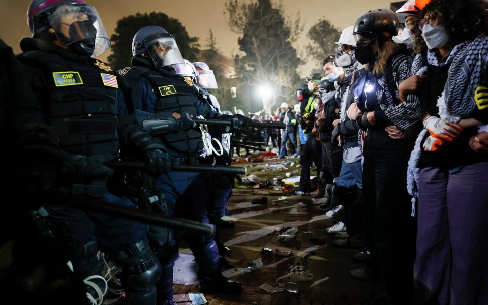 Police face pro-Palestinian students after destroying part of the encampment barricade on the campus of the University of California in  Los Angeles on May 2