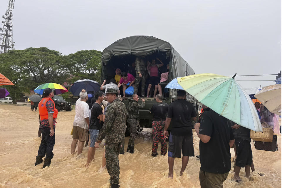 In this photo released by National Disaster Management Agency, the army evacuate residents on Chaah town in Segamat, in southern Johor state, Malaysia, Wednesday, March 1, 2023. Rescuers in boats plucked flood victims trapped on rooftops and hauled others to safety as incessant rain submerged homes and villages in parts of Malaysia, leading to over 26,000 people evacuated as of Thursday. (National Disaster Management Agency via AP)