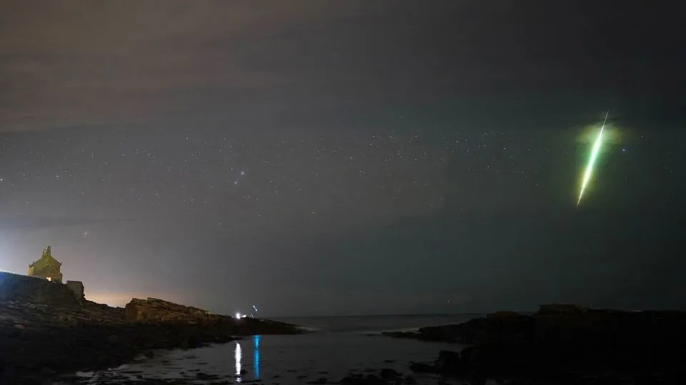 A meteor streaks across the sky during the Draconid meteor shower as seen over Howick rocks in Northumberland in northeast England in October 2021. - Owen Humphreys/PA Media/FILE