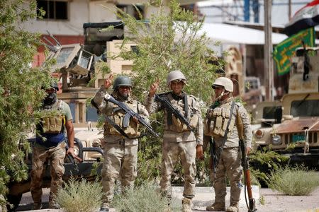 Iraqi army soldiers carry their weapons as they gather in the center of Falluja, Iraq, June 17, 2016. REUTERS/Thaier Al-Sudani