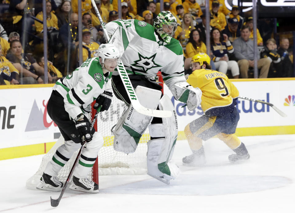 Dallas Stars goaltender Ben Bishop (30) jumps out of the way of defenseman John Klingberg (3), of Sweden, during the second period in Game 2 of an NHL hockey first-round playoff series against the Nashville Predators, Saturday, April 13, 2019, in Nashville, Tenn. Predators left wing Filip Forsberg (9), also of Sweden, looks on. (AP Photo/Mark Humphrey)