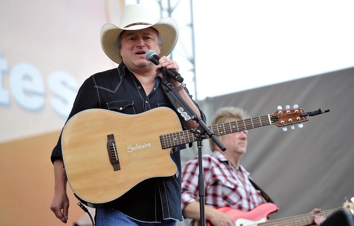 Country singer Mark Chesnutt stands at a microphone onstage.