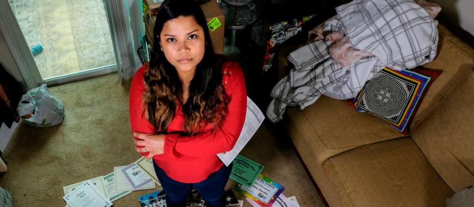 Jessica Bonilla Garcia, 27, stands for a portrait on April 15, 2021 in her apartment in Ridgeland, S.C. with her DACA renewal paperwork in hand. Nine years ago, Garcia used the photos and rewards surrounding her, collected from her life in South Carolina since she was 4, to apply for DACA for the first time. She fills out new forms and pays $495 to renew her status every 21 months.