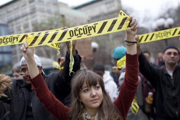 An Occupy Wall Street protester holds up yellow tape with the word "Occupy" on it in New York's Union Square March 21, 2012.