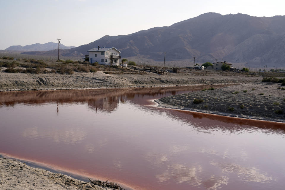 Clouds and nearby mountains are reflected in a polluted canal, once used as a boating dock, along the Salton Sea in Desert Shores, Calif., Wednesday, July 14, 2021. The Salton Sea, California's largest but rapidly shrinking lake, is at the forefront of efforts to make the U.S. a major global player in the production of lithium. (AP Photo/Marcio Jose Sanchez)