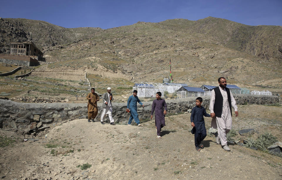 In this Wednesday, May 20, 2020 photo, members of the Aryubi family walk to a graveyard where Dr. Yousuf Aryubi and two siblings who lost their lives to COVID-19 are buried, in Kabul, Afghanistan. Dr. Aryubi's family assumed they just had a bad cold, as one after another, they came down with fevers and coughs -- all because one of the Afghan capital's main hospitals never told them the results of his coronavirus test. Their tragedy points to how a broken-down health system, slow government response and public attitudes have left Afghanistan deeply vulnerable to the global pandemic. (AP Photo/Rahmat Gul)