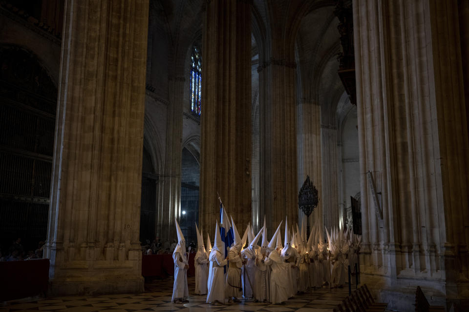 Penitents from "La Candelaria" brotherhood walk across the Seville cathedral as they takes part in a procession, Spain, Tuesday, April 4, 2023. Hundreds of processions take place throughout Spain during the Easter Holy Week. (AP Photo/Emilio Morenatti)