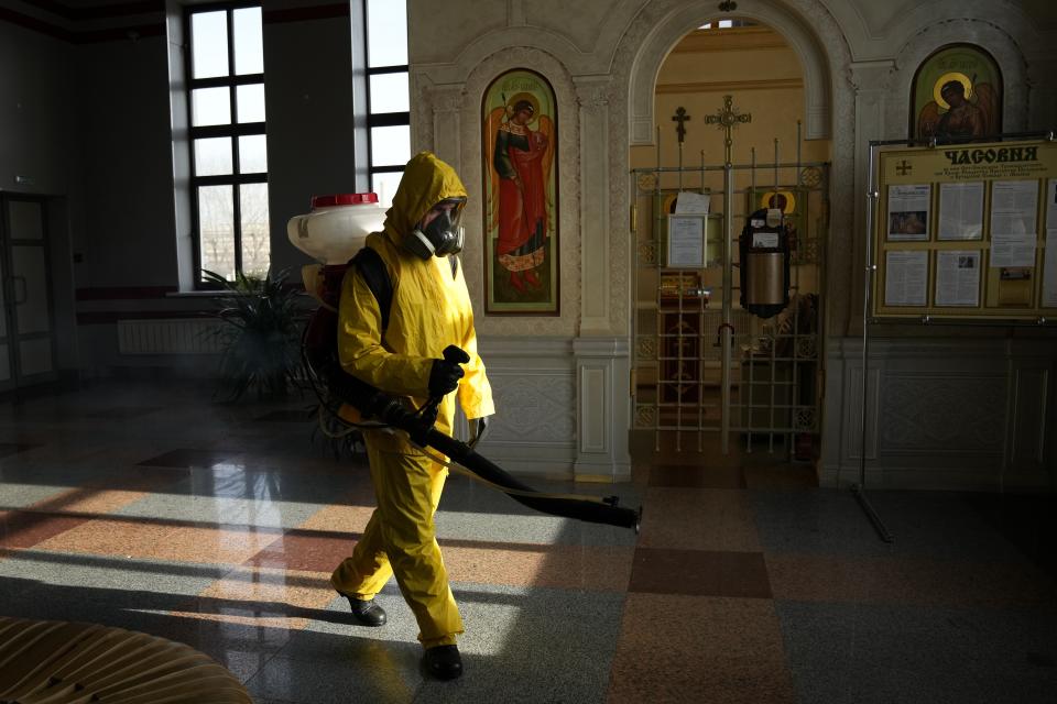 An employee of the Federal State Center for Special Risk Rescue Operations of Russia Emergency Situations disinfects an area near a station chapel inside Savyolovsky railway station in Moscow, Russia, Tuesday, Oct. 26, 2021. The daily number of COVID-19 deaths in Russia hit another high Tuesday amid a surge in infections that forced the Kremlin to order most Russians to stay off work starting this week. (AP Photo/Alexander Zemlianichenko)