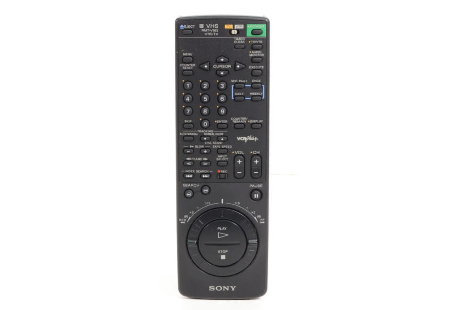 Sony VHS remote control with numerous buttons including channel, volume, play, stop, and a large circular dial for navigation