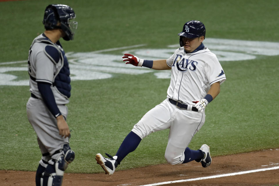 Tampa Bay Rays' Yoshi Tsutsugo, of Japan, right, scores in front of New York Yankees catcher Gary Sanchez on a sacrifice fly by Michael Perez off Yankees pitcher Adam Ottavino during the eighth inning of a baseball game Friday, Aug. 7, 2020, in St. Petersburg, Fla. (AP Photo/Chris O'Meara)