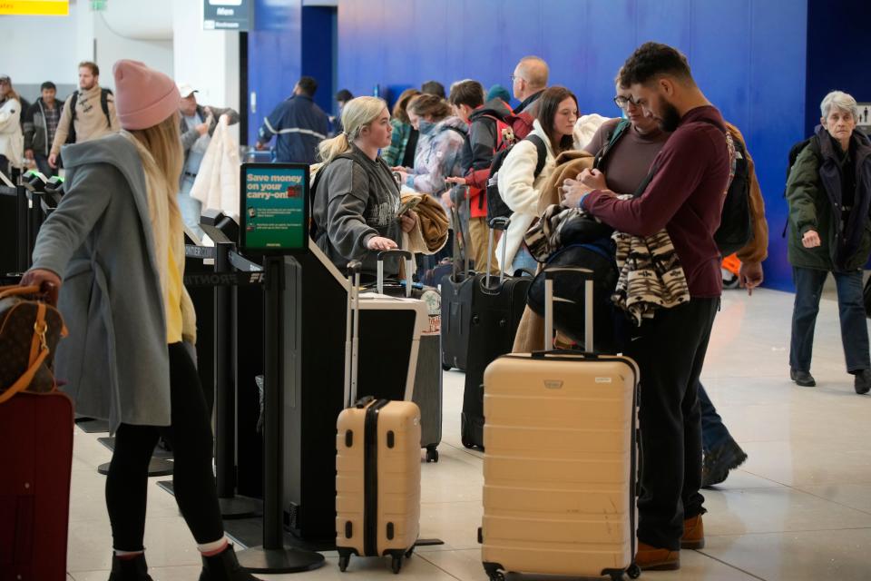 Travelers queue up at the check-in kiosks for Frontier Airlines in Denver International Airport Friday, Dec. 30, 2022, in Denver.