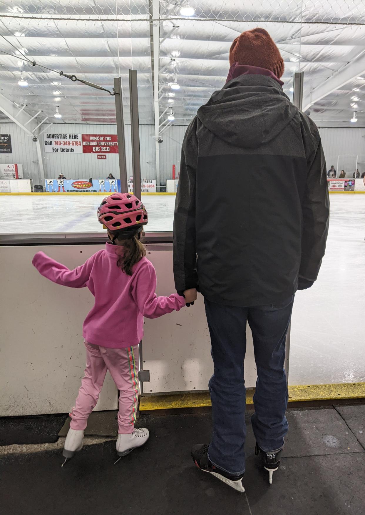 Abbey's husband waits with his daughter for his first skating class.