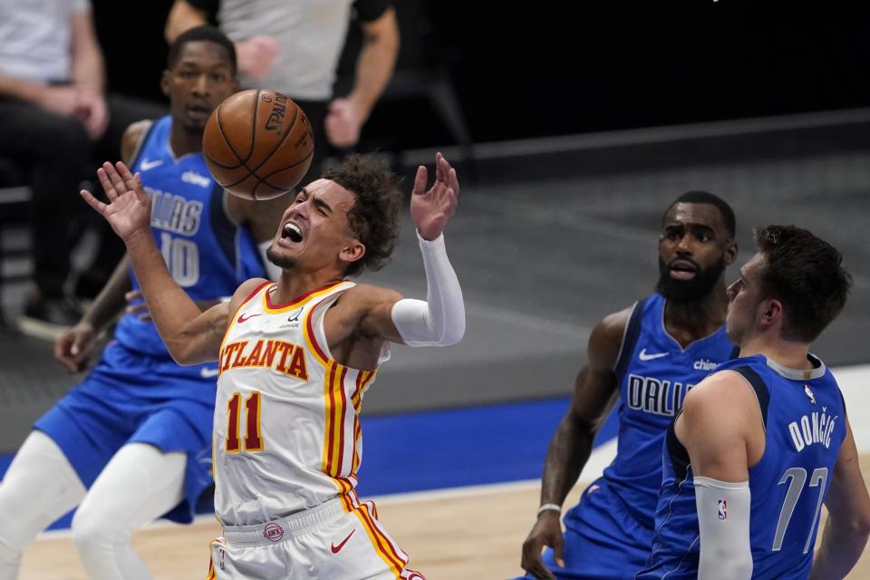 Atlanta Hawks' Trae Young is fouled going to the basket between Dallas Mavericks' Dorian Finney-Smith, Tim Hardaway Jr. and Luka Doncic during their game in Dallas on Feb. 10, 2021. (AP Photo/Tony Gutierrez)