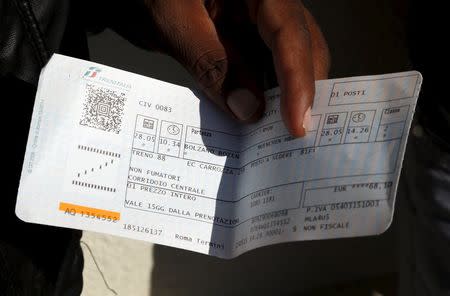 A migrant shows his train ticket to Germany, as he waits to take the train from the Italian border at Bolzano railway station, Italy May 28, 2015. REUTERS/Stefano Rellandini