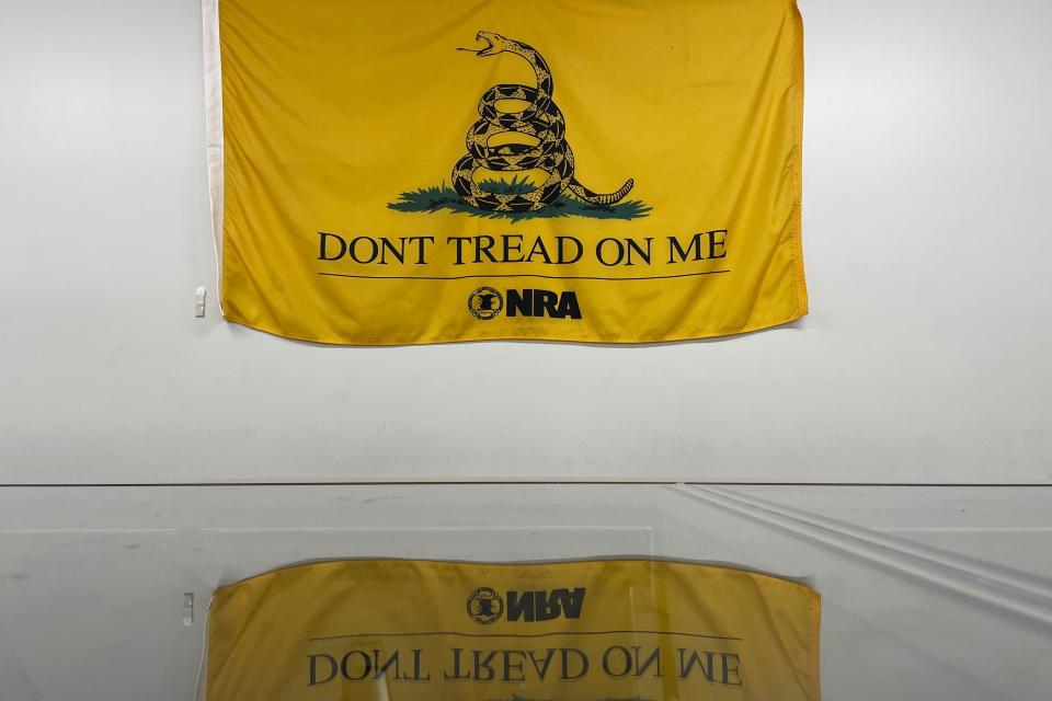 The Gadsden flag is reflected in the glass counter at Los Ranchos Gun Shop near Albuquerque, N.M, on Monday, Sept. 11, 2023. (AP Photo/Susan Montoya Bryan)