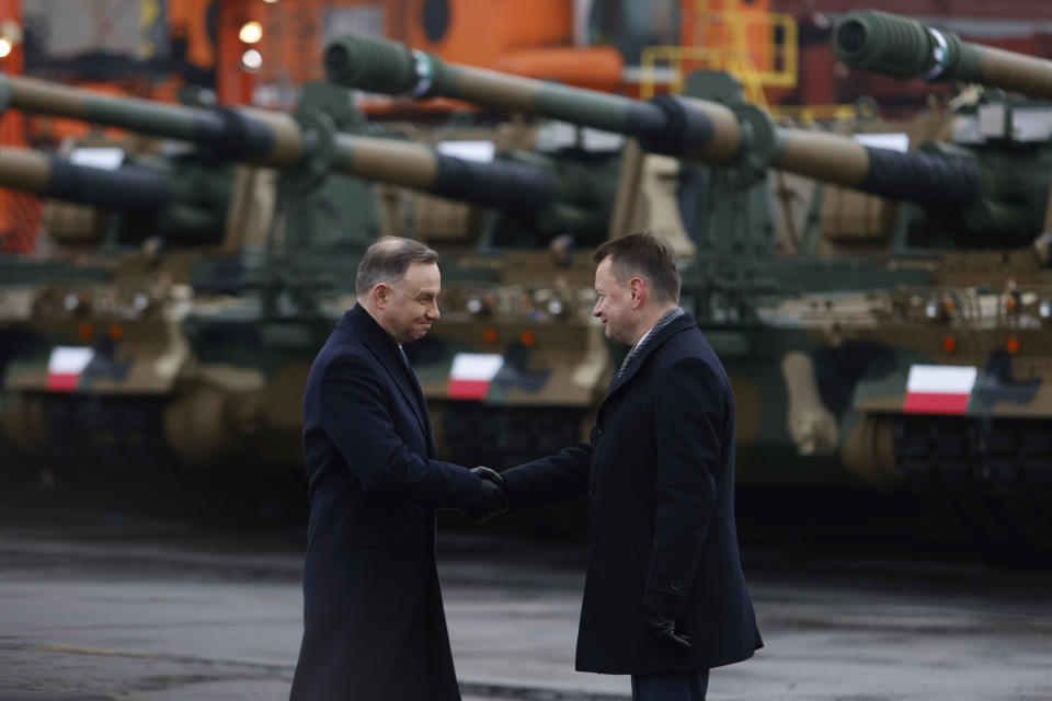 Poland's president Andrzej Duda, left, and Polish Minister of Defense Mariusz Blaszczak, right, shake hands during a press conference in the Polish Navy port of Gdynia, Poland, Tuesday, Dec. 6, 2022. Poland's President Andrzej Duda and the defense minister on Tuesday welcomed the first delivery of tanks and howitzers from South Korea, hailing the swift implementation of a deal signed in the summer in the face of the war in neighbouring Ukraine. (AP Photo/Michal Dyjuk)