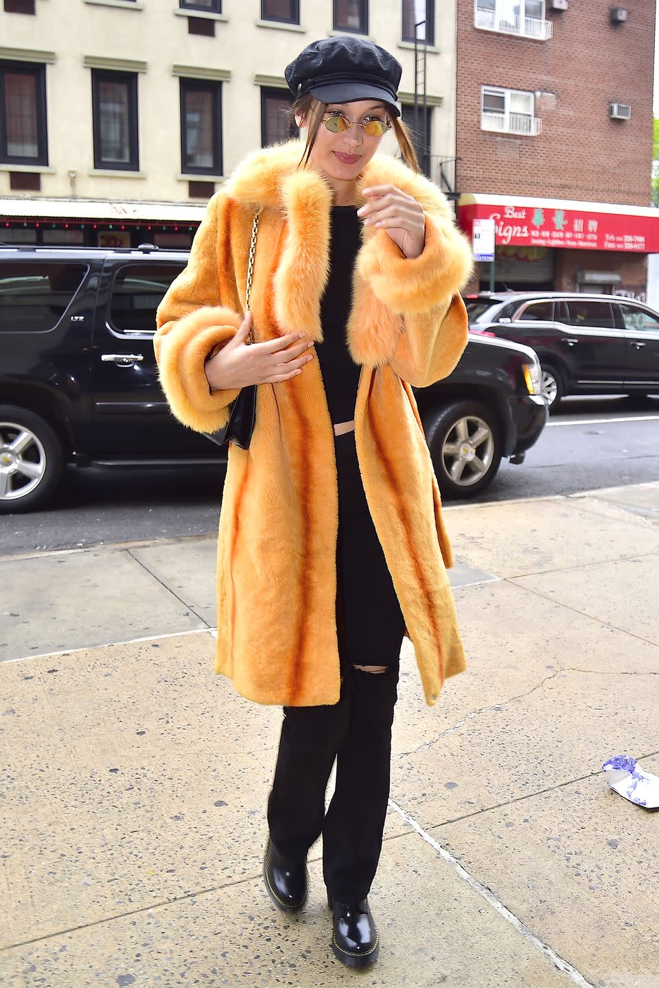 <p>In an citrus colored fur coat with a black top, flared jeans, Dr. Martens boots, round mirrored sunglasses, and a black hat while out in New York City. </p>