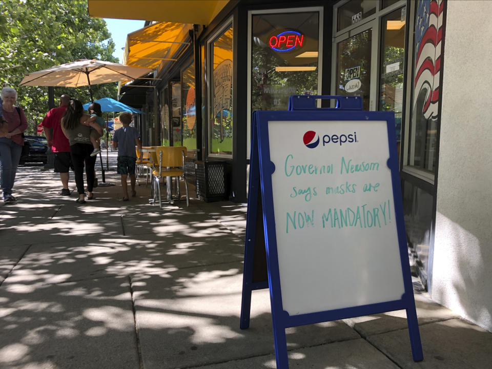 A sign reads "Governor Newsom says masks are Now Mandatory," outside of Linda's Soda Bar and Grill in Yuba City, Calif., Thursday, July 9, 2020. Sutter County was one of the first counties to reopen its economy when it defied Gov. Gavin Newsom's stay-at-home order in May to allow restaurants, hair salons, gyms and shopping malls to reopen. But Thursday, the county was added to a state watch list because of its rising number of coronavirus cases and hospitalizations. That will eventually trigger another round of restrictions, forcing bars to close and indoor operations to cease at restaurants and other public places for three weeks. (AP Photo/Adam Beam)