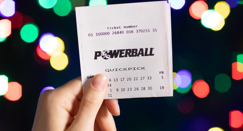 A Powerball ticket is held in the air.