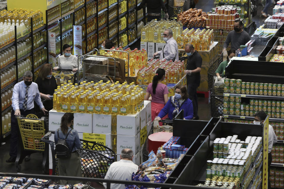 People shop at a supermarket as they begin to stock up on provisions, in Beirut, Lebanon, Wednesday, May 13, 2020. Lebanese rushed to food stores to stock up on vegetables and basic items, hours before the government was to reinstate a four-day nationwide lockdown on Wednesday, following a spike in reported coronavirus cases. (AP Photo/Bilal Hussein)