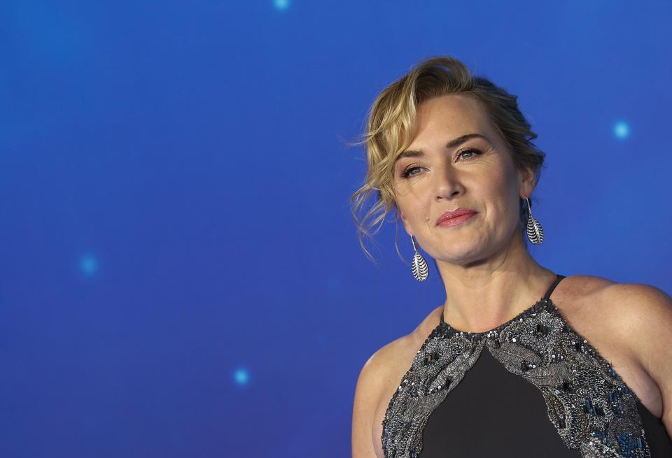 Winslet soft smiles in a black dress on the carpet for "Avatar" with a curly updo