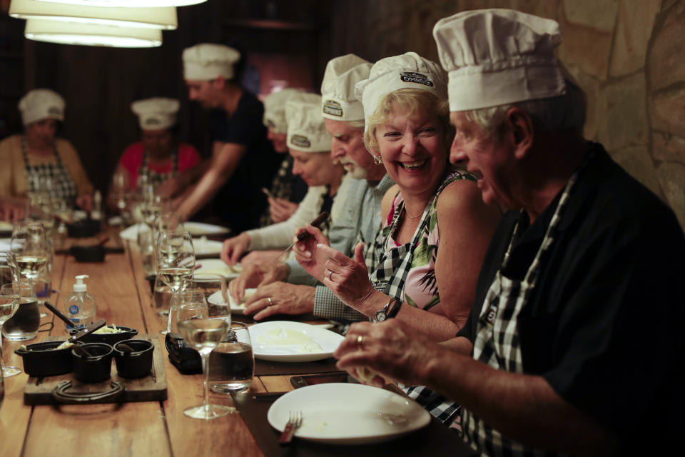 In this March 20, 2017 photo Jane Andrews, from U.S, second left, smiles during an activity called "The Argentine Experience" in Buenos Aires, Argentina. Tourists participating in "The Argentine Experience" have the chance to learn about the local cuisine, wine and traditions during a dinner in Buenos Aires. (AP Photo/Natacha Pisarenko)