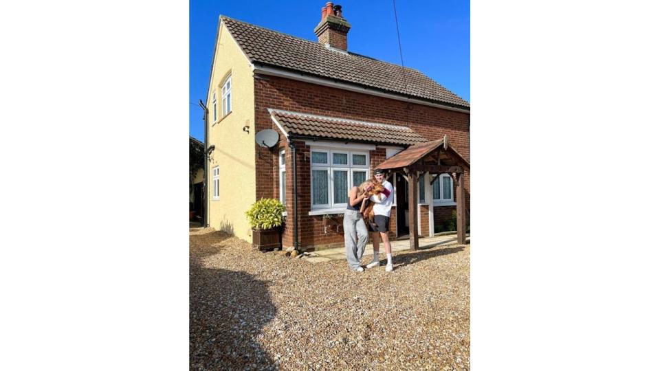 Tasha Ghouri and Andrew Le Page holding a dog while standing outside a house