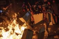 Protesters throw cartons to a burning barricade during clashes with police in Barcelona, Spain, Tuesday, Oct. 15, 2019. Spain's Supreme Court on Monday convicted 12 former Catalan politicians and activists for their roles in a secession bid in 2017, a ruling that immediately inflamed independence supporters in the wealthy northeastern region. (AP Photo/Bernat Armangue)