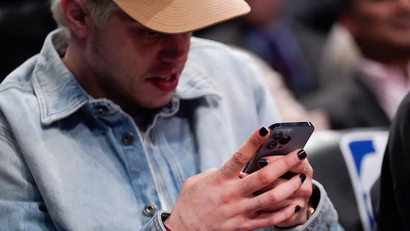 Comedian Pete Davidson looks at his smartphone during the first half of an NBA basketball game between the Brooklyn Nets and the New York Knicks, Nov. 30, 2021, in New York.