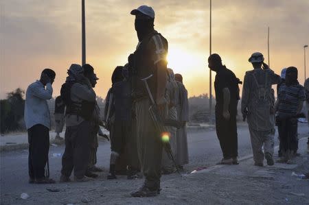 Fighters of the Islamic State of Iraq and the Levant (ISIL) stand guard at a checkpoint in the northern Iraq city of Mosul, in this June 11, 2014 file photo. REUTERS/Stringer/Files