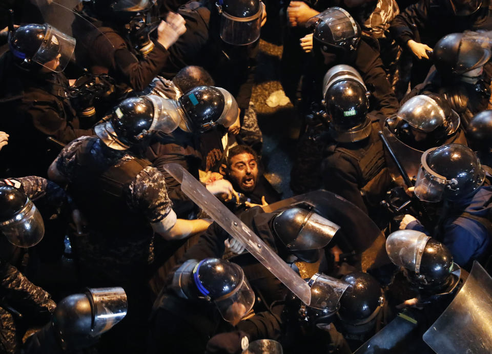 Riot police arrest an anti-government protester who was protesting outside a police headquarters demanding the release of those taken into custody the night before, outside the police headquarters, in Beirut, Lebanon, Wednesday, Jan. 15, 2020. Lebanese security forces arrested 59 people, the police said Wednesday, following clashes overnight outside the central bank as angry protesters vented their fury against the country's ruling elite and the worsening financial crisis. (AP Photo/Hussein Malla)