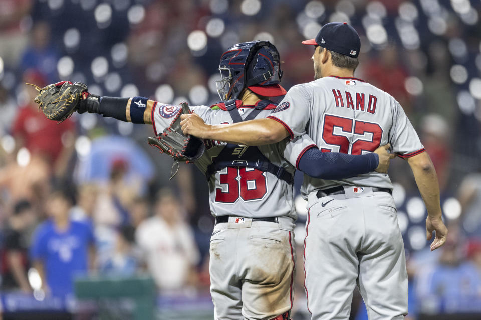 Washington Nationals closing pitcher Brad Hand (52) and catcher Tres Barrera (38) wave to the dugout after the Nationals defeated the Philadelphia Phillies 6-4 in a baseball game Tuesday, July 27, 2021, in Philadelphia. (AP Photo/Laurence Kesterson)