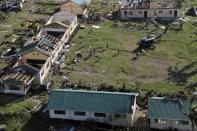 An aerial view shows damaged structures as residents unload relief goods from a helicopter after Typhoon Haiyan hit a village in Panay island in northern Iloilo Province, central Philippines November 9, 2013. Typhoon Haiyan, possibly the strongest storm ever to hit land, has devastated the central Philippine city of Tacloban, killing at least 100 people and destroying most houses in a surge of flood water and high winds, officials said on Saturday. The toll of death and damage is expected to rise sharply as rescue workers and soldiers reach areas cut off by the massive storm, now barrelling out of the Philippines towards Vietnam . REUTERS/Leo Solinap (PHILIPPINES - Tags: DISASTER ENVIRONMENT)