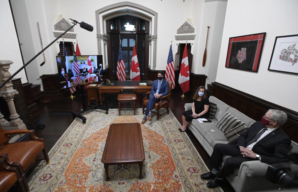 Canadian Prime Minister Justin Trudeau, Deputy Prime Minister and Minister of Finance Chrystia Freeland, and Foreign Affairs Minister Marc Garneau watch television as they meet virtually with United States President Joe Biden from his office on Parliament Hill in Ottawa, Ontario, Tuesday, Feb. 23, 2021. (Adrian Wyld/The Canadian Press via AP)