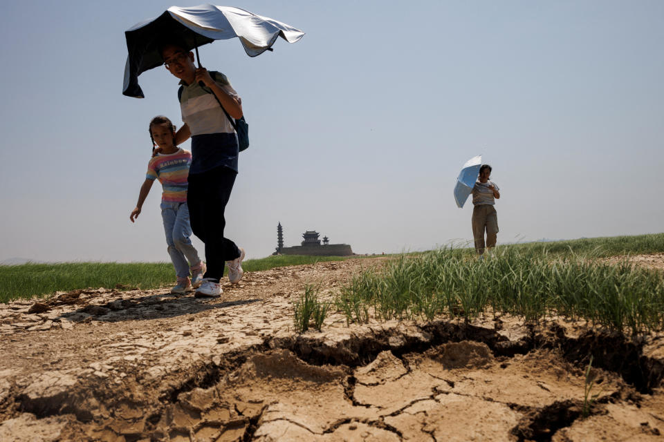 People walk across a dried-up section of Poyang Lake that is facing low water levels due to a regional drought in Lushan, Jiangxi province, China, August 24, 2022.  REUTERS/Thomas Peter