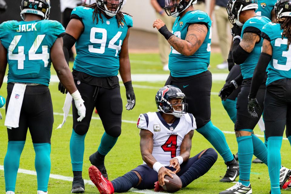 Jaguars players including Dawaune Smoot (94) and DaVon Hamilton (52) and Myles Jack (44) surround Deshaun Watson after a sack during a 2020 game at TIAA Bank Field.