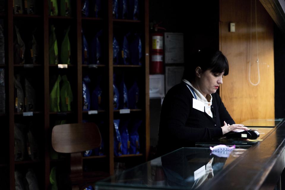 An employee uses a payment device in a coffee shop still affected by the power outage, in Buenos Aires, Argentina, Monday, June 17, 2019. As lights turned back on across Argentina, Uruguay and Paraguay after a massive blackout that hit tens of millions people, authorities were still largely in the dark about what caused the collapse of the interconnected grid and were tallying the damage from the unforeseen disaster. (AP Photo/Tomas F. Cuesta)