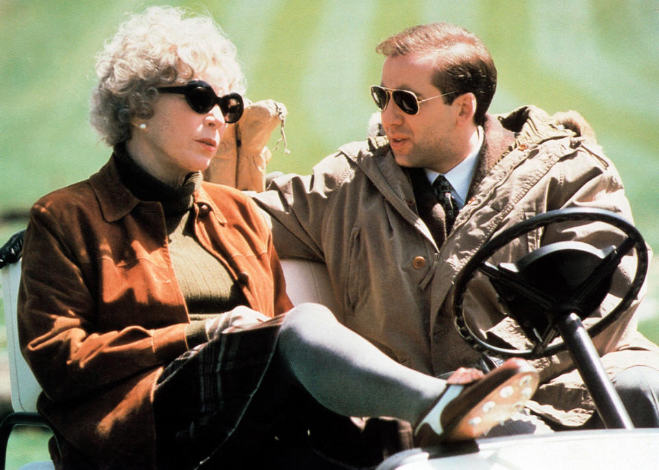 Shirley MacLaine and Nicolas Cage sitting in a golf cart.